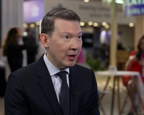 Man in a dark suit being interviewed at a conference or expo, with a microphone clipped to his lapel.
