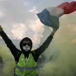 Protester holding a smoke flare and waving a French flag amid green smoke