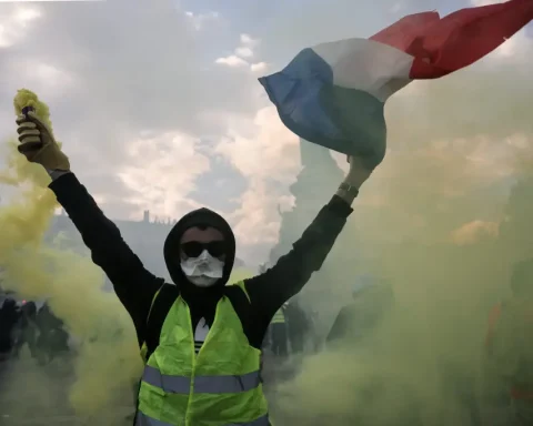 Protester holding a smoke flare and waving a French flag amid green smoke