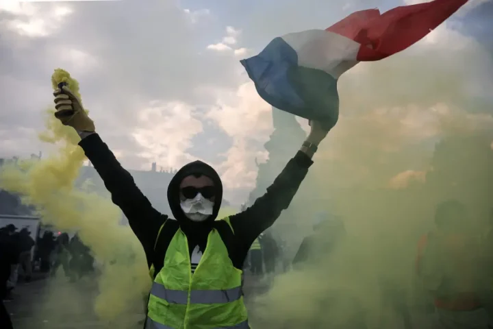 Protester holding a smoke flare and waving a French flag amid green smoke