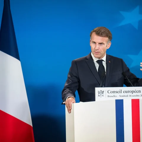French President Emmanuel Macron gesturing while speaking at a podium