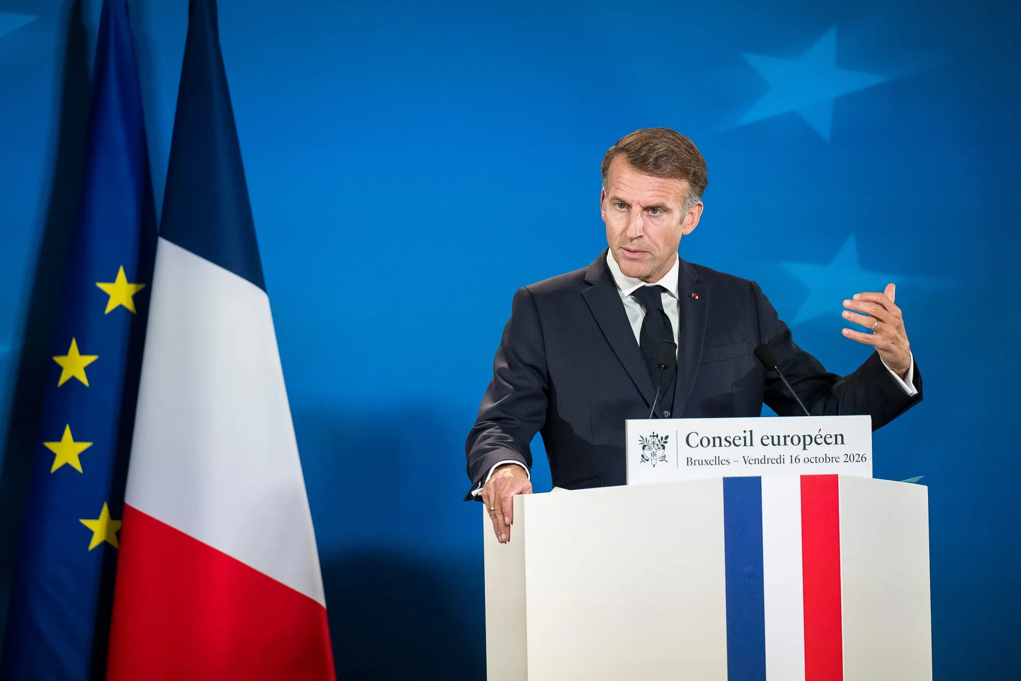 French President Emmanuel Macron gesturing while speaking at a podium