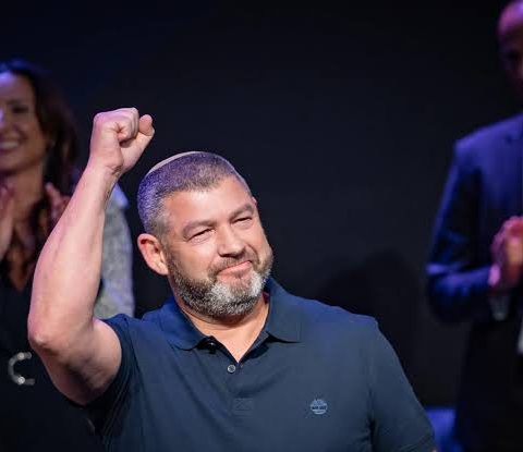 Ofer Winter raising his fist on stage at a rally