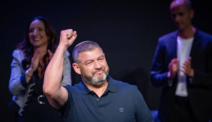 Ofer Winter raising his fist on stage at a rally