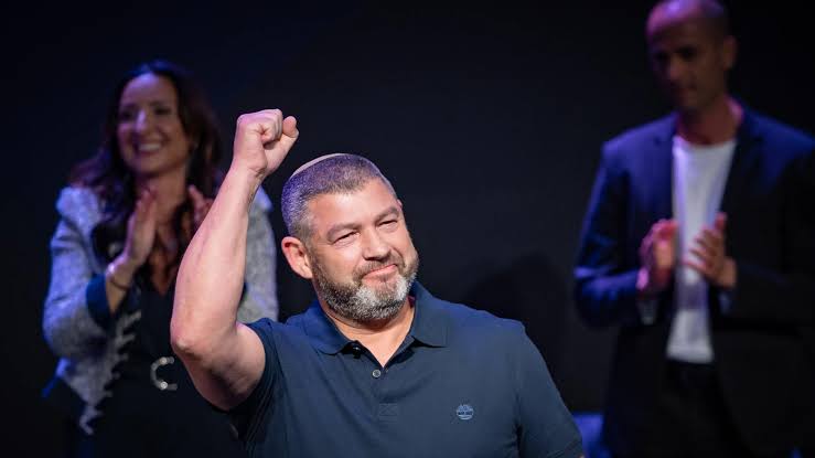 Ofer Winter raising his fist on stage at a rally