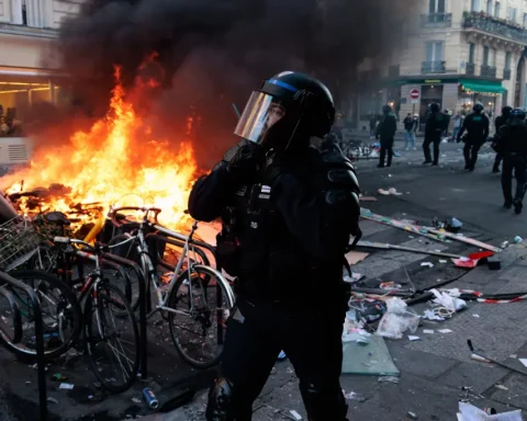 Riot police officer stands near a burning barricade during unrest in Paris