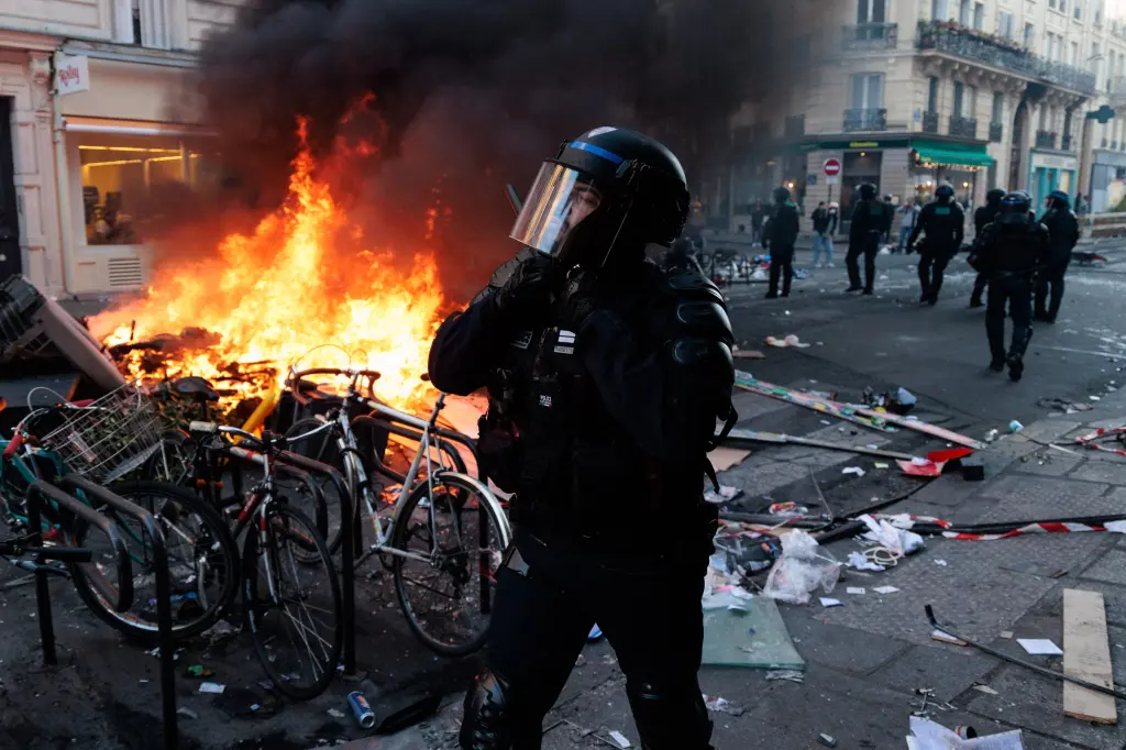 Riot police officer stands near a burning barricade during unrest in Paris