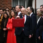 UK Chancellor holding up the red budget box outside Downing Street