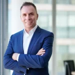 Wizz Air CEO Jozsef Varadi standing with arms crossed in an office